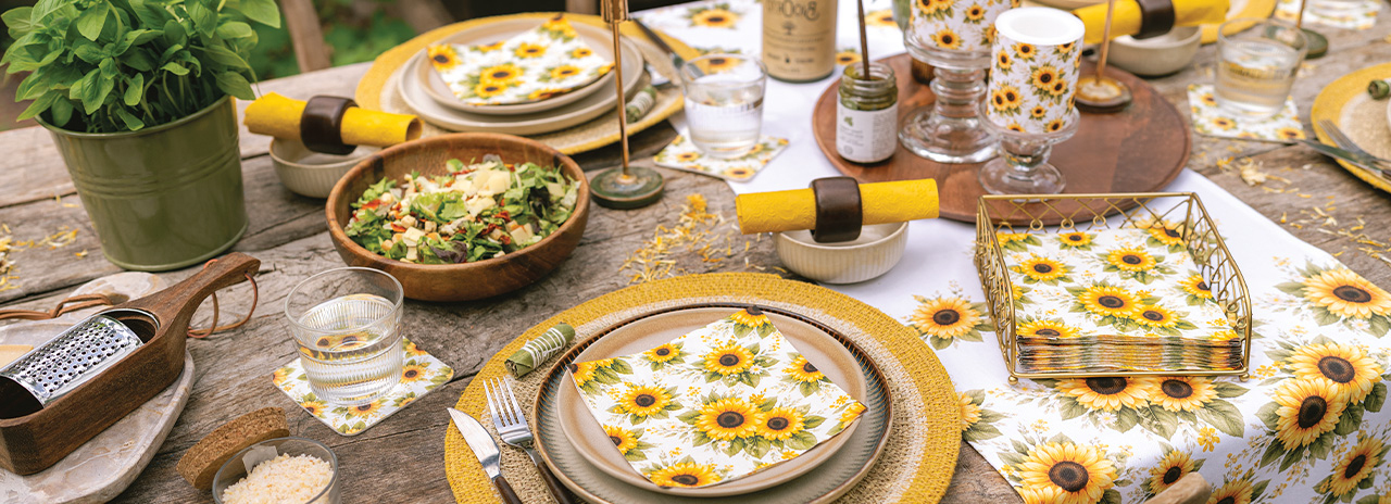 Warmly set table featuring a cheerful 'Sunflower pattern' tableware, napkins, and sunflowers.