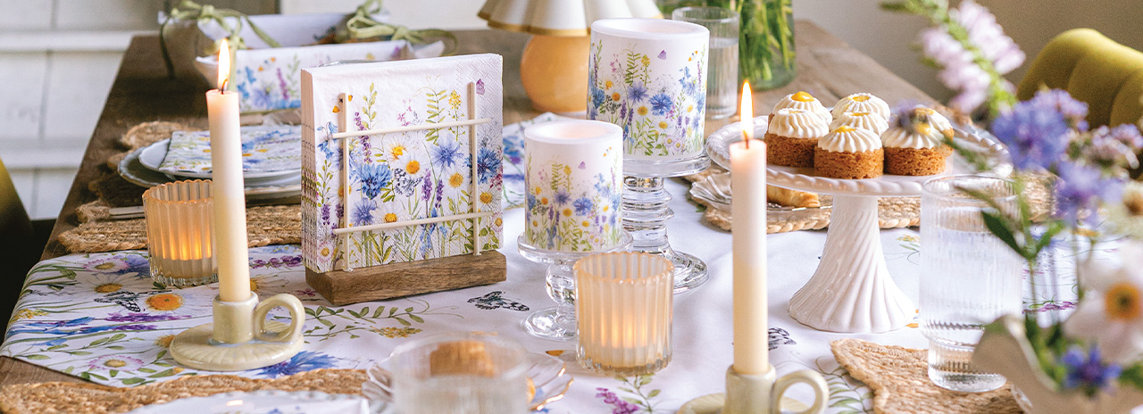 Sfeervol gedekte eettafel met 'Wild meadow flowers' servies, kaarsen en servetten.
