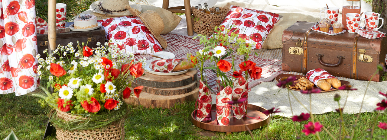 Atmosphärisches Outdoor-Picknick-Setup mit 'Poppy all over' Dekoration und Geschirr.