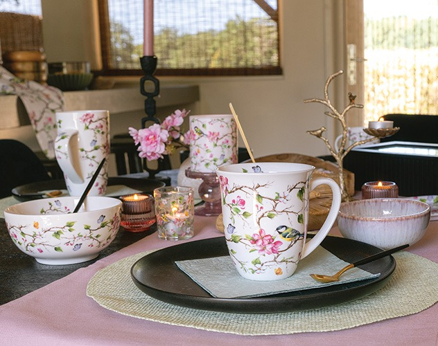 Sfeervol gedekte tafel met 'Lively blossom tree' mok, kommen, kaarsen en roze details.
