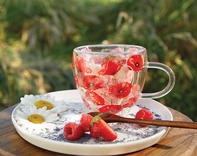 Double-walled glass with red 'Poppy all over' poppy pattern on a plate with fruit.