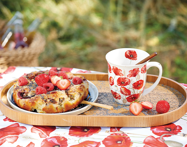 Mug from the 'Poppy all over' series next to a cake on a wooden tray.