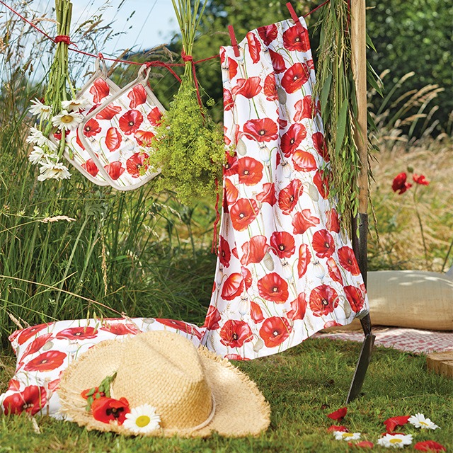Kitchen towel and potholders with 'Poppy all over' poppy design hanging on a clothesline.