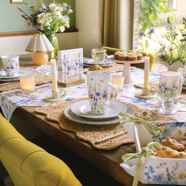 Spring table with Wild meadow flowers mugs, napkins in a napkin holder, candle and table runner with wildflowers