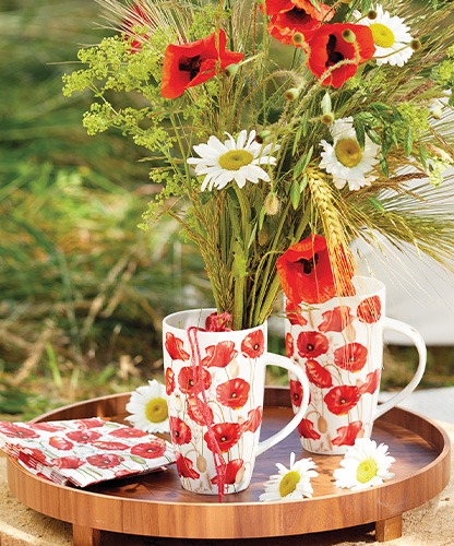 Two tall mugs with 'Poppy all over' print filled with wildflowers on a wooden tray.