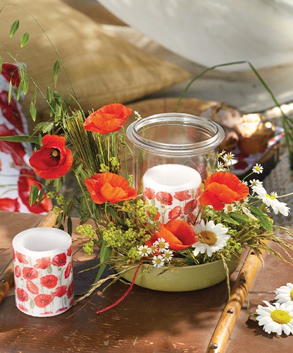 Atmospheric candles with 'Poppy all over' poppy print displayed among wildflowers.